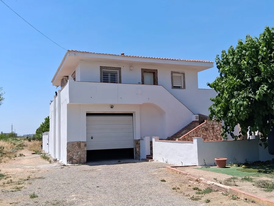 Casa de fachada blanca con garaje y escalera exterior